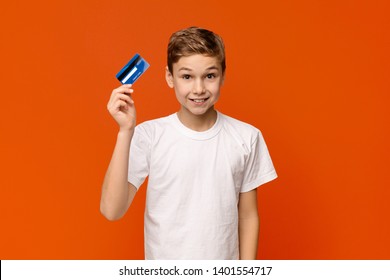 Kids Banking. Cute Boy Holding Credit Card, Orange Studio Background