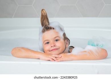 Kids bath. Happy funny kid bathed in the bath. Child in shower. Kids face in the bathroom with foam. Portrait of baby bathing in a bath full of foam.