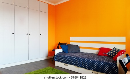 Kids Bedroom In Orange And Blue Colors With Two Beds And Built-in Wardrobe