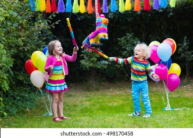 Kids birthday party. Group of children hitting pinata and playing with balloons. Family and friends celebrating birthday outdoors in decorated garden. Outdoor celebration with active games. - Powered by Shutterstock