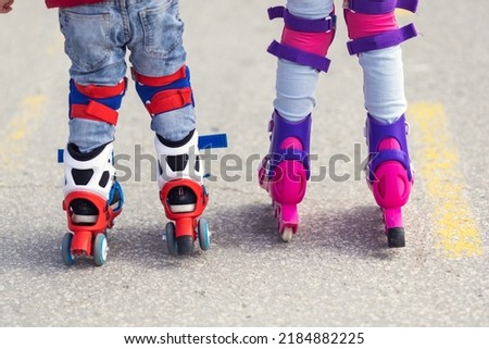 Kids boy and girl having fun outdoor while riding roller skates. Children on rollerblades. Roller skating in the park near seashore.