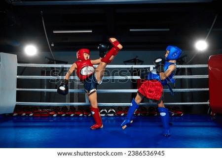 Kids, boys, fighters in sport uniform exercising kickboxing tricks fighting in ring at gym. Young professional sportsmen. Concept of sport, healthy lifestyle, hobby, fitness workout, competition.