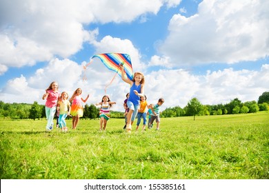 Kids Boys And Girls With Kite Running In The Par On Sunny Summer Day