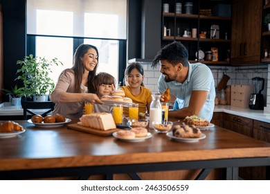 Kids at breakfast with parents. Mother is serving donuts on a plate. Cheerful family moments at home. - Powered by Shutterstock