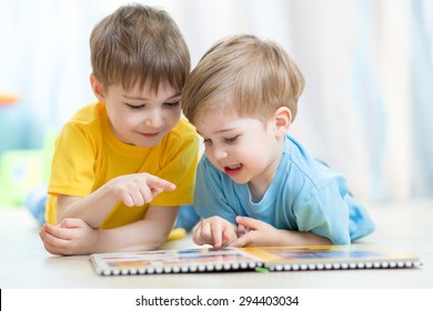 Kids brothers practice reading together looking at book laying on the floor
