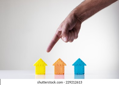 kids building blocks made into a shape of a house with a mans hand picking what house he wants - Shutterstock ID 229212613