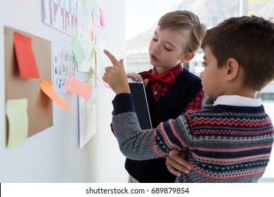 Kids as business executives discussing over bulletin board in office - Powered by Shutterstock