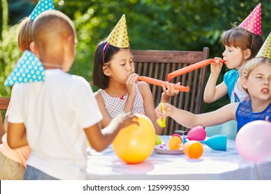 Kids celebrate together at garden party in summer with balloons and noise makers