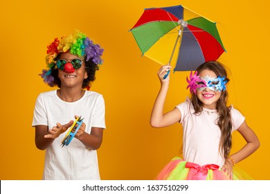 Kids Celebrating Carnival Together At Yellow Background. Two Children Celebrating Carnival In Brazil. 