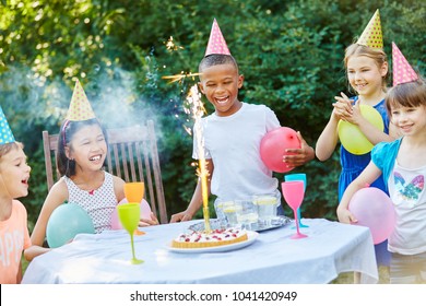 Kids celebrating together birthday party with table fireworks on cake