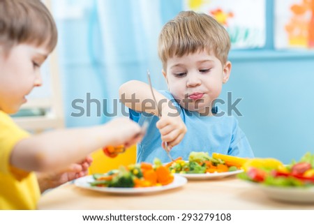 kids children eating vegetables in kindergarten or at home