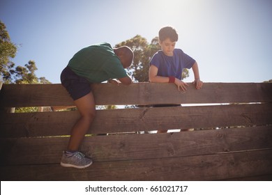 Kids climbing wooden wall during obstacle course in boot camp - Powered by Shutterstock