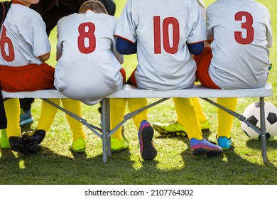 Kids In Colourful Sporty Clothes Sitting In A Team On Soccer Bench. Boys In Football Jersey Shirts Ready To Play Tournament Game