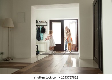 Kids Coming Back Home With Parents Mom And Dad, Smiling Cute Children Siblings With Backpacks Returning From School Entering Big Modern Hall, Family Of Four Happy To Arrive At The House Together