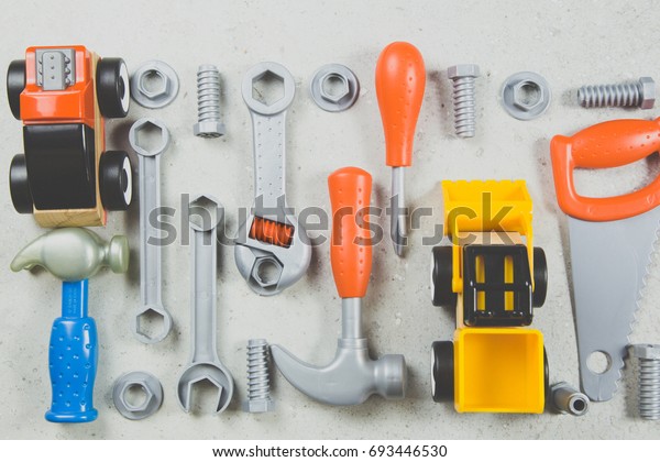 Kids construction toys tools , Colorful kids toys\
border. Plastic toy tools,car. bolts and nuts on white background\
as frame. Top view