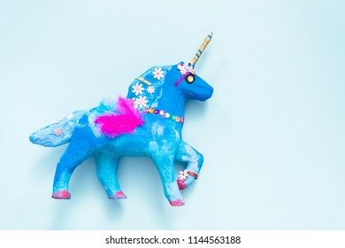 Kids Craft. Painted Blue And Decorated With Jewels And Feathers Paper Mache Unicorn.