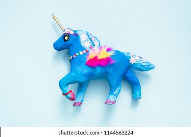 Kids Craft. Painted Blue And Decorated With Jewels And Feathers Paper Mache Unicorn.