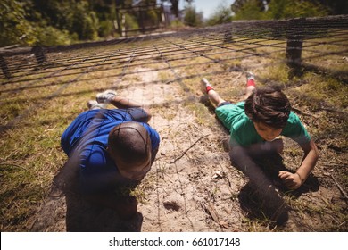 Kids crawling under the net during obstacle course in boot camp - Powered by Shutterstock