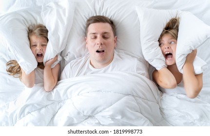 Kids, dad sleep together in bed. Father is snoring hard, girls, daughters are plugging ears with pillow. Disorders, joint sleeping. Insomnia, night bedtime. Wake up,rise to kindergarten, school,work. - Powered by Shutterstock