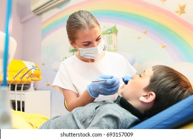 Kids dentist examines the teeth of a child in the office. Photos in the interior.