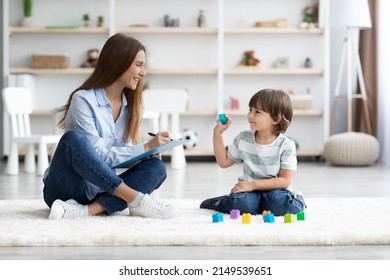 Kids Development And Checkup. Cute Little Boy Playing With Colorful Blocks, Young Professional Woman Psychologist Making Notes About Mental Health, Free Space