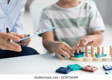 Kids development classes. Close up shot of unrecognizable little boy playing logical educational game during psychological consultation, specialist taking notes, empty space for text