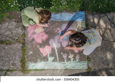 Kids Drawing With Chalk On Sidewalk