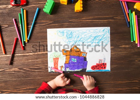 Kids drawing and a lot of painting tools  on a wooden background