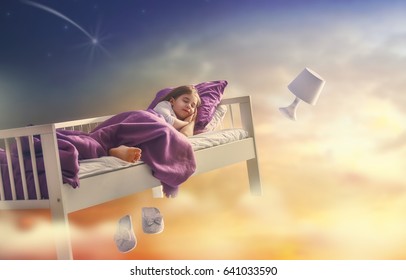 Kids dreams. Cute child girl is flying in her bed trough star sky.