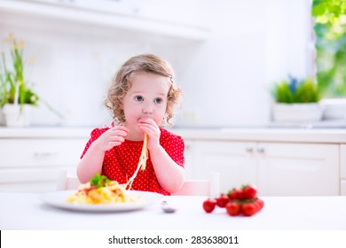 Kids Eat Pasta. Healthy Lunch For Children. Toddler Kid Eating Spaghetti Bolognese In A White Kitchen At Home. Preschooler Child Cooking Noodles With Tomato And Pepper For Dinner. Food For Family.