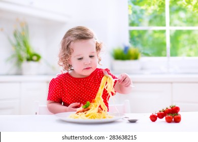 Kids Eat Pasta. Healthy Lunch For Children. Toddler Kid Eating Spaghetti Bolognese In A White Kitchen At Home. Preschooler Child Cooking Noodles With Tomato And Pepper For Dinner. Food For Family.