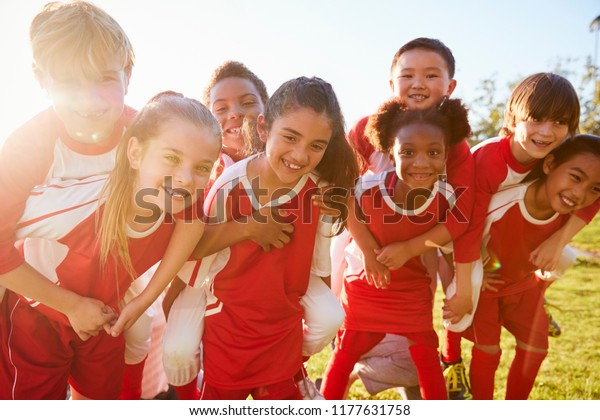Kids in elementary school sports team\
piggybacking outdoors