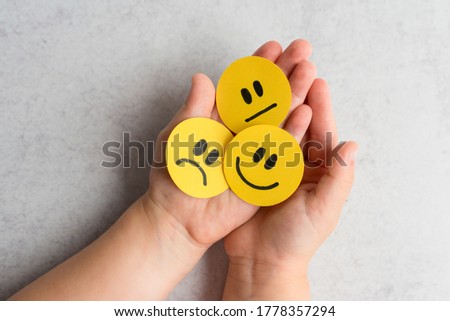 Kids emotions. Kids Hands with yellow smiley, sad and unsatisfied paper faces. Emotional intelligence concept. 