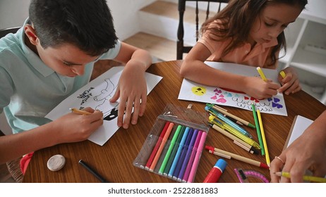 Kids enjoying drawing with colorful markers at a table. They express creativity and imagination in a relaxed, educational home setting. Ideal for back-to-school themes. - Powered by Shutterstock