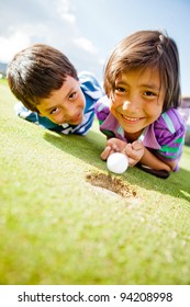 Kids Enjoying Playing Golf Lying On The Field And Smiling