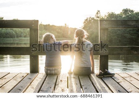 Kids enjoying summer at the lake sitting on the dock