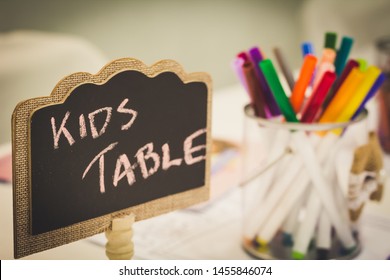 Kids Entertainment Table At A Wedding With Colorful Markers In A Jar And A Chalkboard Sign