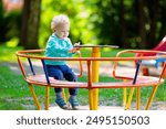 Kids explore nature. Children play in sunny park. Child on playground in beautiful summer park. Outdoor fun for active family. Kid on swing and slide.