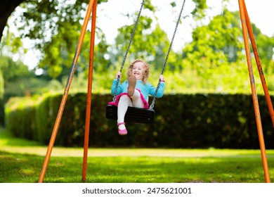 Kids explore nature. Children play in sunny park. Child on playground in beautiful summer park. Outdoor fun for active family. Kid on swing and slide.