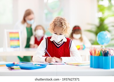 Kids In Face Mask In School Class. Child Back To School After Coronavirus Lockdown. Primary Child In Covid-19 Pandemic. Safety And Virus Spread Prevention. Student In Surgical Mask. Social Distancing.