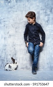 Kid's fashion. Modern nine year old boy posing with rabbit. Clothes for children. Easter holidays. 