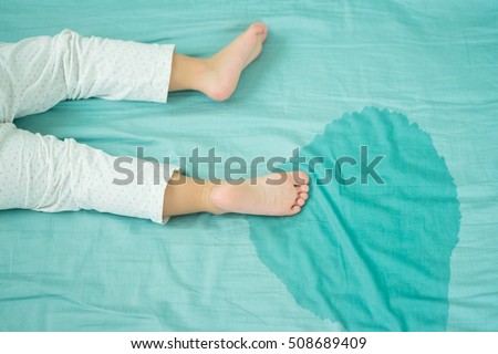 Kid's feet and pee in a mattress.Little girl feet and pee in bed sheet on the morning.Child development concept.