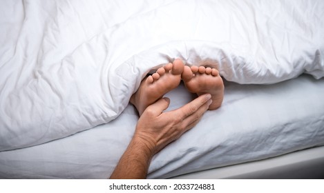 Kid's Feet Under White Blanket With Father's Hand Tickling To Wake Up. Sleeping In Bed. Gentle Touch Of Child's Feet. Waking Up To Go To School. Tickling For Fun. Kids Taking A Rest With Bare Feet.