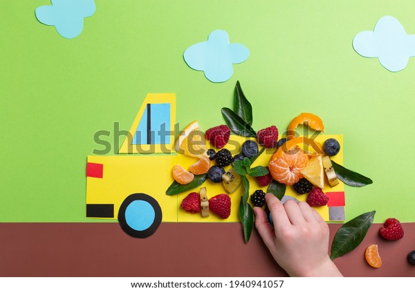 Kids food art concept:\
paper craft truck with berries and fruits on green concept top\
view, flat lay