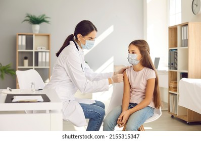 Kids Getting Shots At The Hospital. Nurse At A New Modern Clinic Giving An Injection To A Child In A Face Mask. Doctor Giving A Covid 19 Vaccine To A Teenage Girl Who's Wearing A Mouth Covering