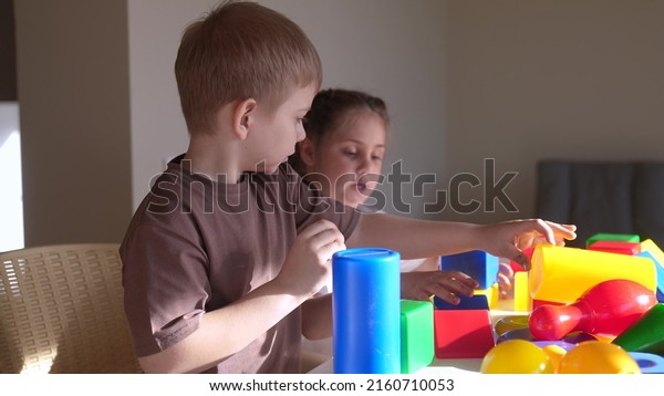 kids girl and baby play in kindergarten. a group of
children play toys cubes and cars on the table in kindergarten.
happy family preschool education concept. nursery boy baby toddler
indoor home