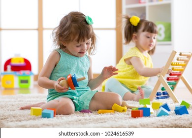 Kids Girls Are Engaging In Daycare. Two Toddler Children Playing With Educational Toys In Kindergarten.