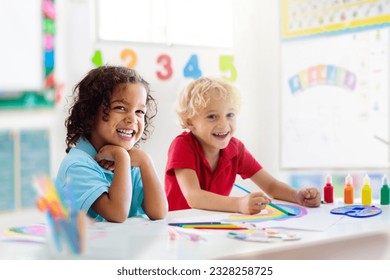 Kids go back to school. Interracial group of children of mixed age in classroom. Students learn to read and write. Preschooler or kindergarten kid with teacher. Child learning letters with flash cards