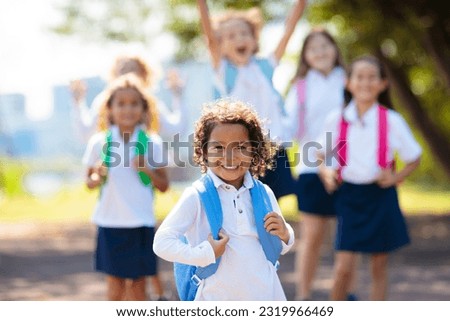 Kids go back to school. Interracial group of children of mixed age run and cheer on the first day of new academic year. Start of school holiday. Preschooler or kindergarten kid. Child in school yard.