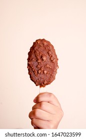 Kids Hand Hold Ice Cream Stick Chocolate Vanilla And Almonds Isolated On Peach